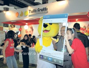 PENGUNJUNG bergambar bersama maskot Tutti Frutti yang turut serta dalam FIM 2014 di Pusat Perdagangan Dunia Putra, Kuala Lumpur, semalam. 