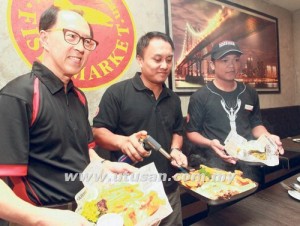 Davy Wee (kiri) dan Mohd. Amir Ariff (tengah ) menunjukkan hidangan yang disajikan oleh restoran itu pada majlis pelancaran pembukaan The Manhattan Fish Market di KB Mall, Kota Bharu, semalam.